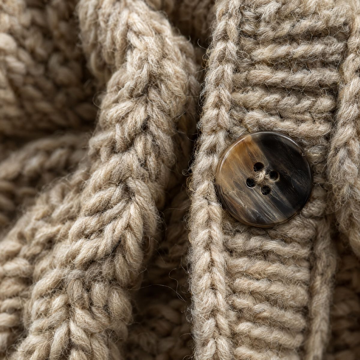 Close-up of a cable-knit texture and a dark horn button